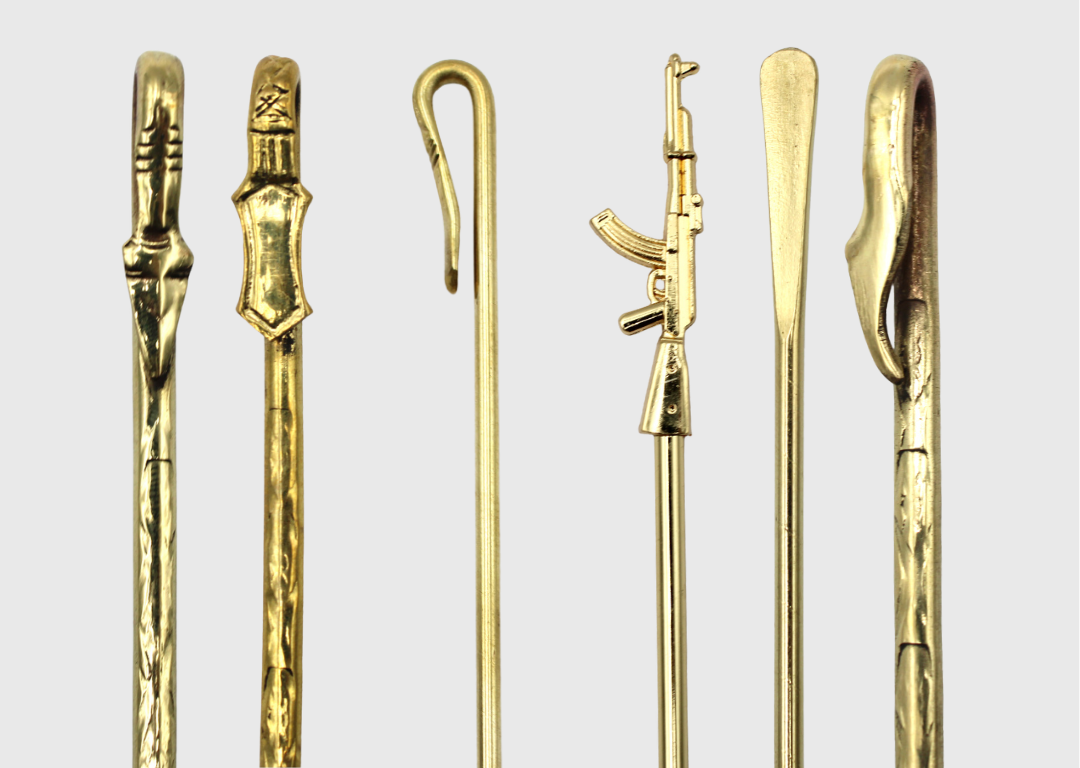 A set of traditional Sikh baaj (salai) pins in different shapes and designs, made of golden metal, displayed vertically on a plain background.